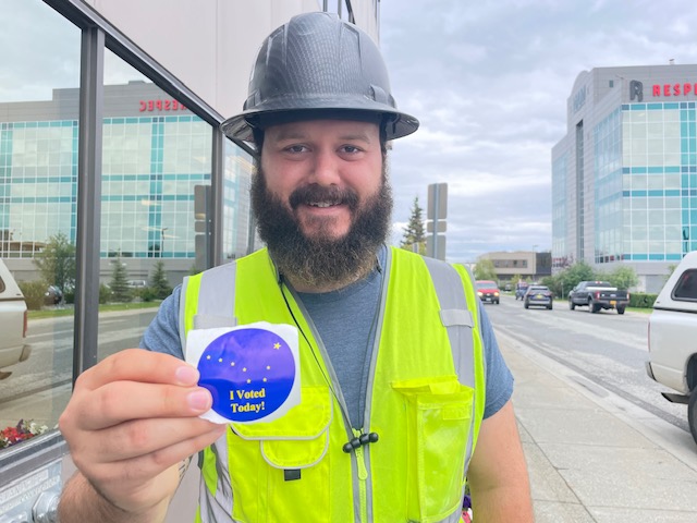 An Alaskan voter holding an I voted sticker